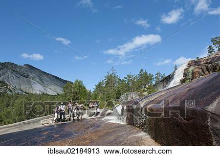 Stock Image - Hiking, trekking, hiking group standing at a waterfall, granite rocks at Mt Roholtsfjell near Vrådal, Vradal, Telemark, Norway, Scandinavia, Northern Europe, Europe. Fotosearch