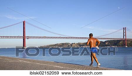 Jogger jogging along on the bank of the Rio Tejo River in front of the Ponte do 25 de Abril bridge in the district of Belem, Lisbon, Portugal, Europe View Large Photo Image Stock Photo - Jogger jogging along on the bank of the Rio Tejo River in front of the Ponte do 25 de Abril bridge in the district of Belem, Lisbon, Portugal, Europe. Fotosearch