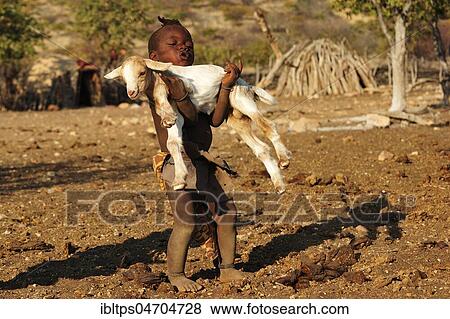 Stock Photo - Little Himba boy carrying a goat, Kunene District, Kaokoveld, Namibia, Africa. Fotosearch