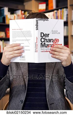 Man holding a book in front of his face, in a bookstore in Regensburg, Bavaria, Germany, Europe View Large Photo Image Picture - Man holding a book in front of his face, in a bookstore in Regensburg, Bavaria, Germany, Europe. Fotosearch