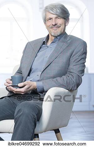 Man sits in his office chair with a coffee cup View Large Photo Image Stock Image - Man sits in his office chair with a coffee cup. Fotosearch