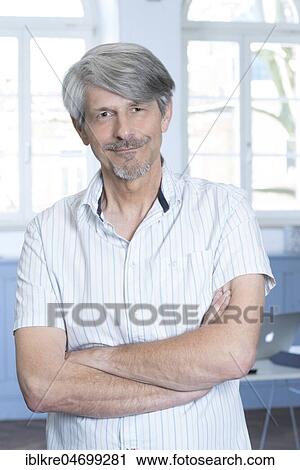 Man standing in his office with his arms crossed View Large Photo Image Stock Image - Man standing in his office with his arms crossed. Fotosearch