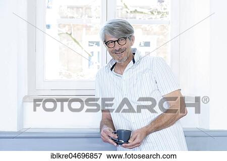 Man with coffee cup at his office window View Large Photo Image Stock Photo - Man with coffee cup at his office window. Fotosearch