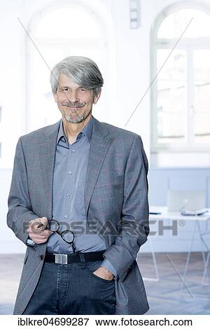 Man with glasses on his hand in front of the window of his office View Large Photo Image Stock Photo - Man with glasses on his hand in front of the window of his office. Fotosearch