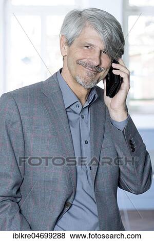 Man with mobile phone in front of his office window View Large Photo Image Stock Photo - Man with mobile phone in front of his office window. Fotosearch