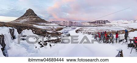 Many photographers photograph Mount Kirkjufell with frozen waterfall Kirkjufellfoss, cloudy sky with sunset, fjord Grundarfjördur, West Iceland, Iceland, Europe View Large Photo Image Picture - Many photographers photograph Mount Kirkjufell with frozen waterfall Kirkjufellfoss, cloudy sky with sunset, fjord Grundarfjördur, West Iceland, Iceland, Europe. Fotosearch