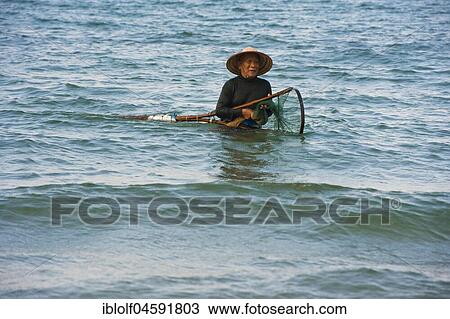 Stock Image - Mussel hunter, shellfish fisherman wearing a straw hat, Cua Dai beach in Hoi An, Vietnam, Asia. Fotosearch