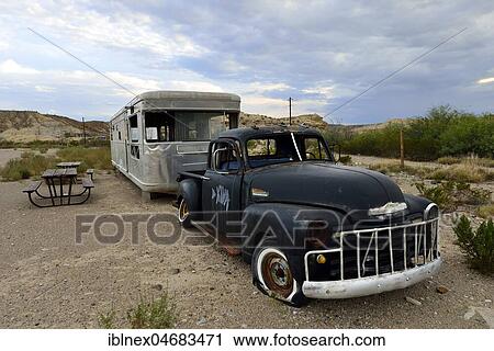 Stock Image - Old rusty Chevrolet with caravan at rest area, Terlingua, Texas, USA, North America. Fotosearch