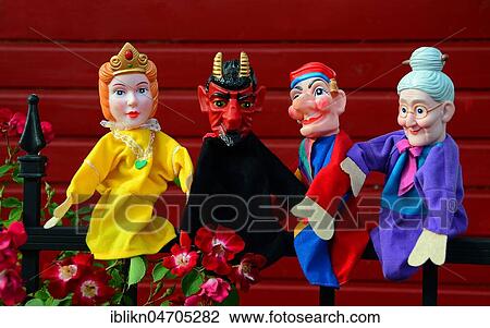 Stock Image - Punch puppets, Punch, Princess, Grandmother and Devil sitting on a metal fence. Fotosearch