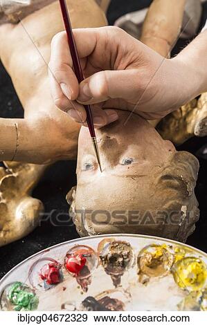 Stock Photo - Restoration studio, restorer, filling material is adapted to the angel's face with brush and paint, Munich, Bavaria, Germany, Europe. Fotosearch