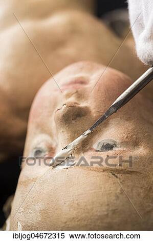 Stock Photography - Restoration studio, restorer, filling compound is applied with spatula to the face of an angel, Munich, Bavaria, Germany, Europe. Fotosearch