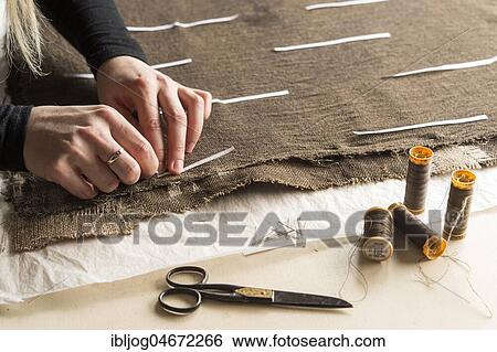 Stock Photograph - Restoration studio, restorer, hand marking seams for finished support fabric on lent scarf with paper strips, Munich, Bavaria, Germany, Europe. Fotosearch