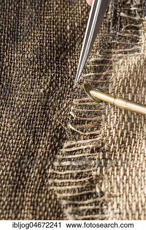 Stock Image - Restoration studio, restorer, With heating spatula and tweezers, linen patch with thread bridge is fixed over crack in lent scarf, Munich, Bavaria, Germany, Europe. Fotosearch