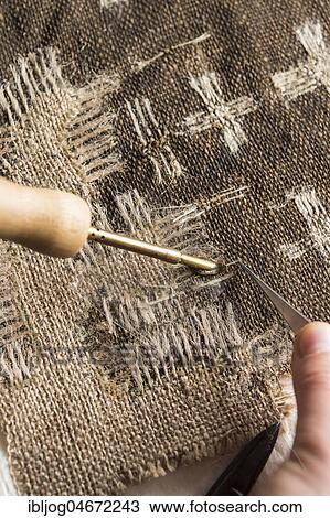 Stock Image - Restoration studio, restorer, With heating spatula and tweezers, linen patch with thread bridge is fixed over crack in lent scarf, Munich, Bavaria, Germany, Europe. Fotosearch