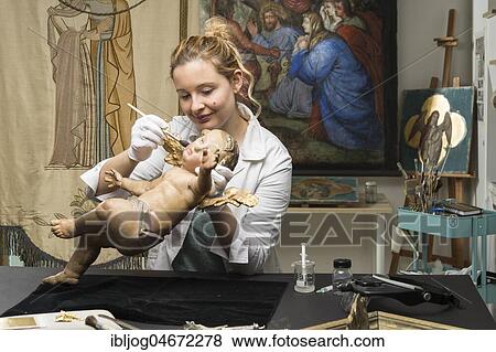 Stock Photo - Restoration studio, restorer, woman cleans an angel with a brush, restored lent scarfs in the back, Munich, Bavaria, Germany, Europe. Fotosearch
