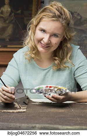 Stock Photograph - Restoration studio, restorer, woman patinates the woven in patch of linen with brush and paint, Munich, Bavaria, Germany, Europe. Fotosearch