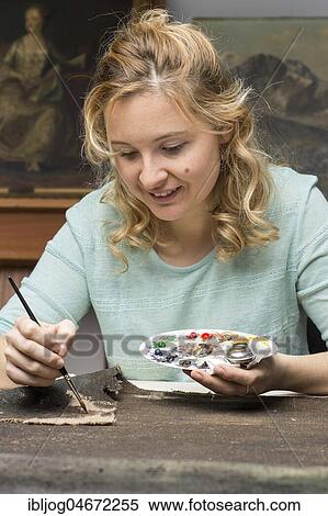 Stock Photography - Restoration studio, restorer, woman patinates the woven in patch of linen with brush and paint, Munich, Bavaria, Germany, Europe. Fotosearch