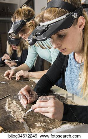 Stock Photo - Restoration studio, women, restorers restore lent scarf on worktable in Atelier, Munich, Bavaria, Germany, Europe. Fotosearch
