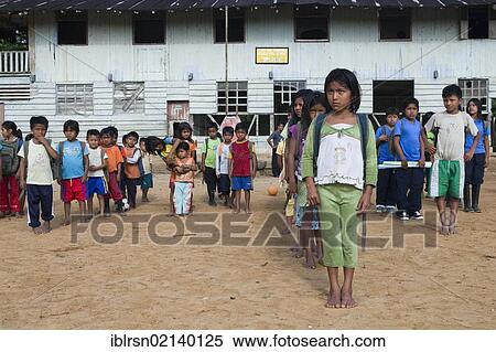 Stock Photography - School children standing in line in the schoolyard before the class begins in a village with no road access in the rainforest of the Oriente, Curaray, Ecuador, South America. Fotosearch