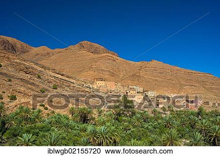 Stock Image - Small clay village on a slope above a palm grove in the Ait Mansour valley, Anti-Atlas mountains, southern Morocco, Morocco, Africa. Fotosearch