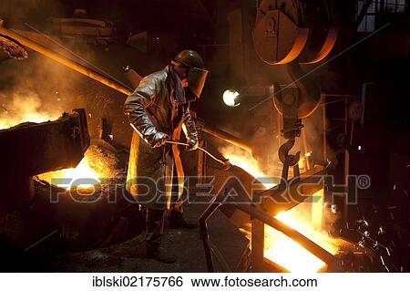 Stock Photograph - Smelter worker wearing protective equipment, employee of the Luitpoldhuette AG, a foundry that specializes in the casting of engine blocks, motor parts and refrigeration compressors, sampling liquid iron in a furnace, in Amberg, Bavaria, Germany, Europe. Fotosearch