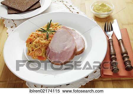 Stock Photography - Smoked pork roast, gammon, Kassel-style pork, with carrots, brown bread and mustard. Fotosearch