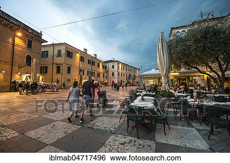 Stock Photograph - Square with restaurants in the old town in the evening, thunderstorm, Lazise, ​​Lake Garda, Lombardy, Italy, Europe. Fotosearch
