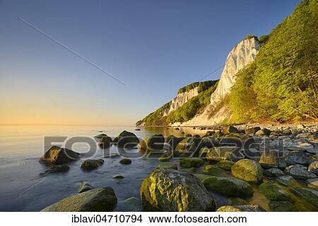 Picture - Sunrise at the Baltic Sea, chalk cliffs in the morning light, boulders on the shore, in front the Königsstuhl, behind the Victoria view, Jasmund National Park, UNESCO World Heritage Site, Rügen Island, Mecklenburg-Western Pomerania, Germany, Europe. Fotosearch