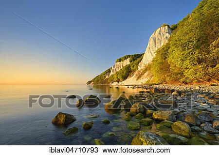 Stock Image - Sunrise at the Baltic Sea, chalk cliffs in the morning light, boulders on the shore, in front the Königsstuhl, behind the Victoria view, Jasmund National Park, UNESCO World Heritage Site, Rügen Island, Mecklenburg-Western Pomerania, Germany, Europe. Fotosearch