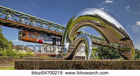 Suspension railway and work of art I'm alive made of polished stainless steel, artist Tony Cragg, Barmen, Wuppertal, Bergisches Land, North Rhine-Westphalia, Germany, Europe View Large Photo Image Stock Photo - Suspension railway and work of art I'm alive made of polished stainless steel, artist Tony Cragg, Barmen, Wuppertal, Bergisches Land, North Rhine-Westphalia, Germany, Europe. Fotosearch