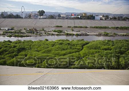 Stock Photography - The polluted Tijuana River as it enters the United States from Mexico, the yellow line in the foreground is the boundary between the United States and Mexico, San Ysidro, California, USA, North America. Fotosearch