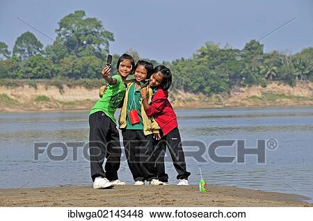 Three girls photographing themselves with a cell phone, Mekong River, Nong Khai, Thailand, Asia, PublicGround, Asia View Large Photo Image Stock Photo - Three girls photographing themselves with a cell phone, Mekong River, Nong Khai, Thailand, Asia, PublicGround, Asia. Fotosearch