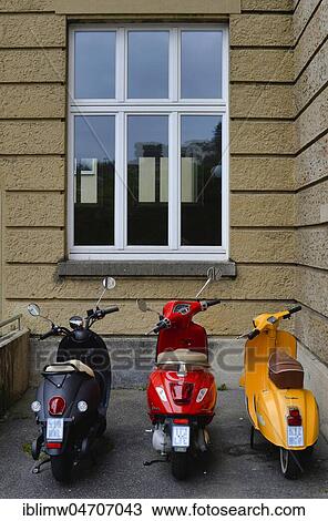 Stock Image - Three scooters in German national colours black-red-gold in a courtyard, Stuttgart, Baden-Württemberg, Germany, Europe. Fotosearch