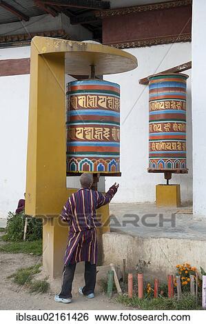 Tibetan Buddhism, believer spinning a large modern prayer wheel, Thimphu, the Himalayas, Kingdom of Bhutan, South Asia, Asia View Large Photo Image Stock Photograph - Tibetan Buddhism, believer spinning a large modern prayer wheel, Thimphu, the Himalayas, Kingdom of Bhutan, South Asia, Asia. Fotosearch