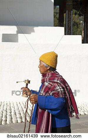 Stock Photo - Tibetan Buddhism, devout elderly woman spinning a prayer wheel, Memorial Chorten, capital of Thimphu, the Himalayas, Kingdom of Bhutan, South Asia, Asia. Fotosearch
