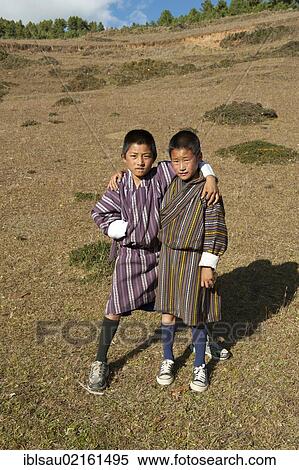 Two boys standing arm in arm on a pasture, traditional costume, Gho, near Gangtey Goenba, Gangteng Monastery, Phobjika Valley, the Himalayas, Bhutan, South Asia, Asia View Large Photo Image Stock Photography - Two boys standing arm in arm on a pasture, traditional costume, Gho, near Gangtey Goenba, Gangteng Monastery, Phobjika Valley, the Himalayas, Bhutan, South Asia, Asia. Fotosearch