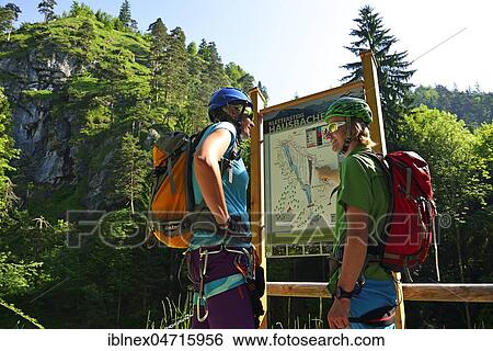 Stock Photograph - Two climbers at information board, via ferrata Hausbachfall, Reit im Winkl, Chiemgau, Bavaria, Germany, Europe. Fotosearch