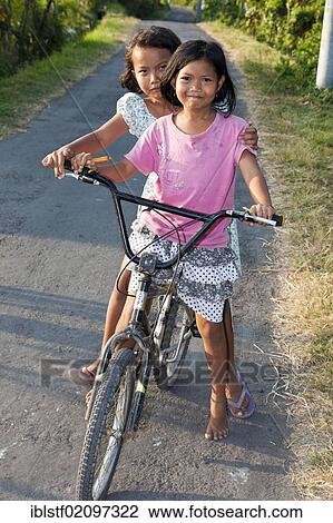 Two girls on a bike, looking curious, Bali, Indonesia, Southeast Asia, Asia View Large Photo Image Stock Image - Two girls on a bike, looking curious, Bali, Indonesia, Southeast Asia, Asia. Fotosearch