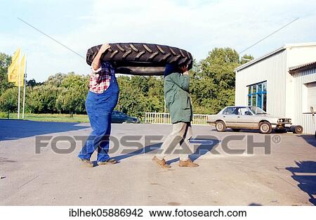 Two men carrying a tractor tire, 2015, Germany, Europe View Large Photo Image Stock Image - Two men carrying a tractor tire, 2015, Germany, Europe. Fotosearch