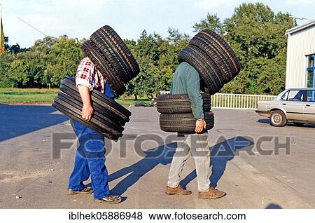 Stock Photo - Two men wearing car tires, 2015, Germany, Europe. Fotosearch