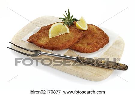 Stock Photo - Viennese Schnitzel with lemon wedges on a wooden board. Fotosearch
