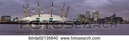 Stock Image - View across the River Thames of Canary Wharf with the Millennium Dome in the foreground, dusk, London, England, United Kingdom, Europe. Fotosearch