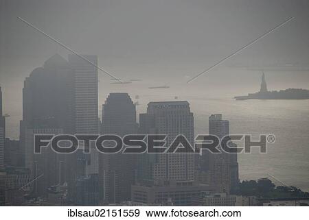 Stock Photo - View from the Empire State Building over skyscrapers towards the Statue of Liberty in fog, mist-shrouded Financial District, gloomy, New York City, USA, North America, America, North America. Fotosearch