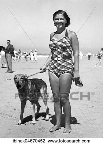 Stock Image - Woman in bathing suit with dog on the beach, 1940s, North Sea, Germany, Europe. Fotosearch