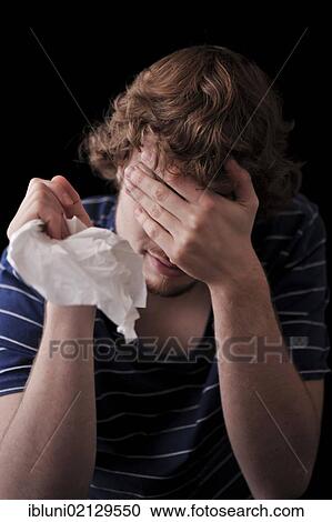 Young man covering face with his hand, holding a handkerchief View Large Photo Image Stock Image - Young man covering face with his hand, holding a handkerchief. Fotosearch