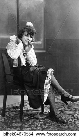 Picture - Young, pretty woman sitting on a chair smoking, 1920s, Germany, Europe. Fotosearch
