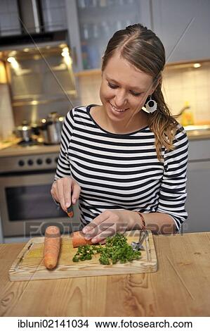 Young woman cutting vegetables in a kitchen View Large Photo Image Picture - Young woman cutting vegetables in a kitchen. Fotosearch