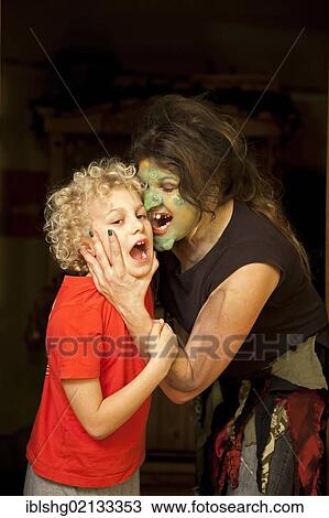 Stock Image - Young woman in a witch costume snatching a little boy. Fotosearch