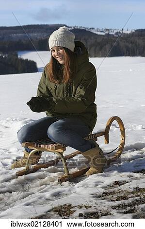 Stock Image - Young woman sitting on a sled, sledging, Black Forest, Baden-Wuerttemberg, Germany, Europe, PublicGround, Europe. Fotosearch