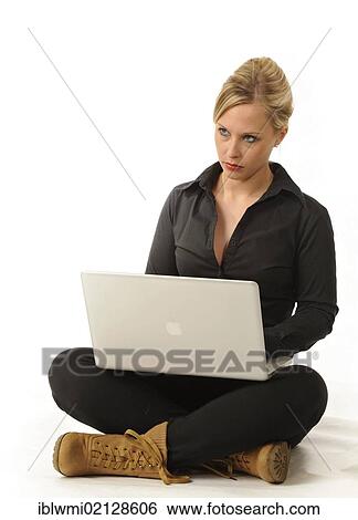 Young woman working on a laptop computer, sitting cross-legged View Large Photo Image Stock Photograph - Young woman working on a laptop computer, sitting cross-legged. Fotosearch